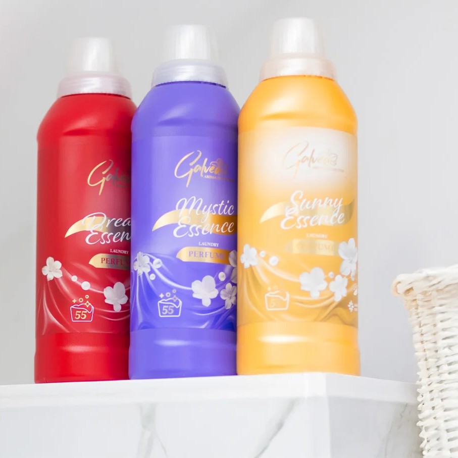 Trzy butelki perfum do tkanin ustawione obok siebie na jasnym tle, prezentujące wersje zapachowe dostępne w linii